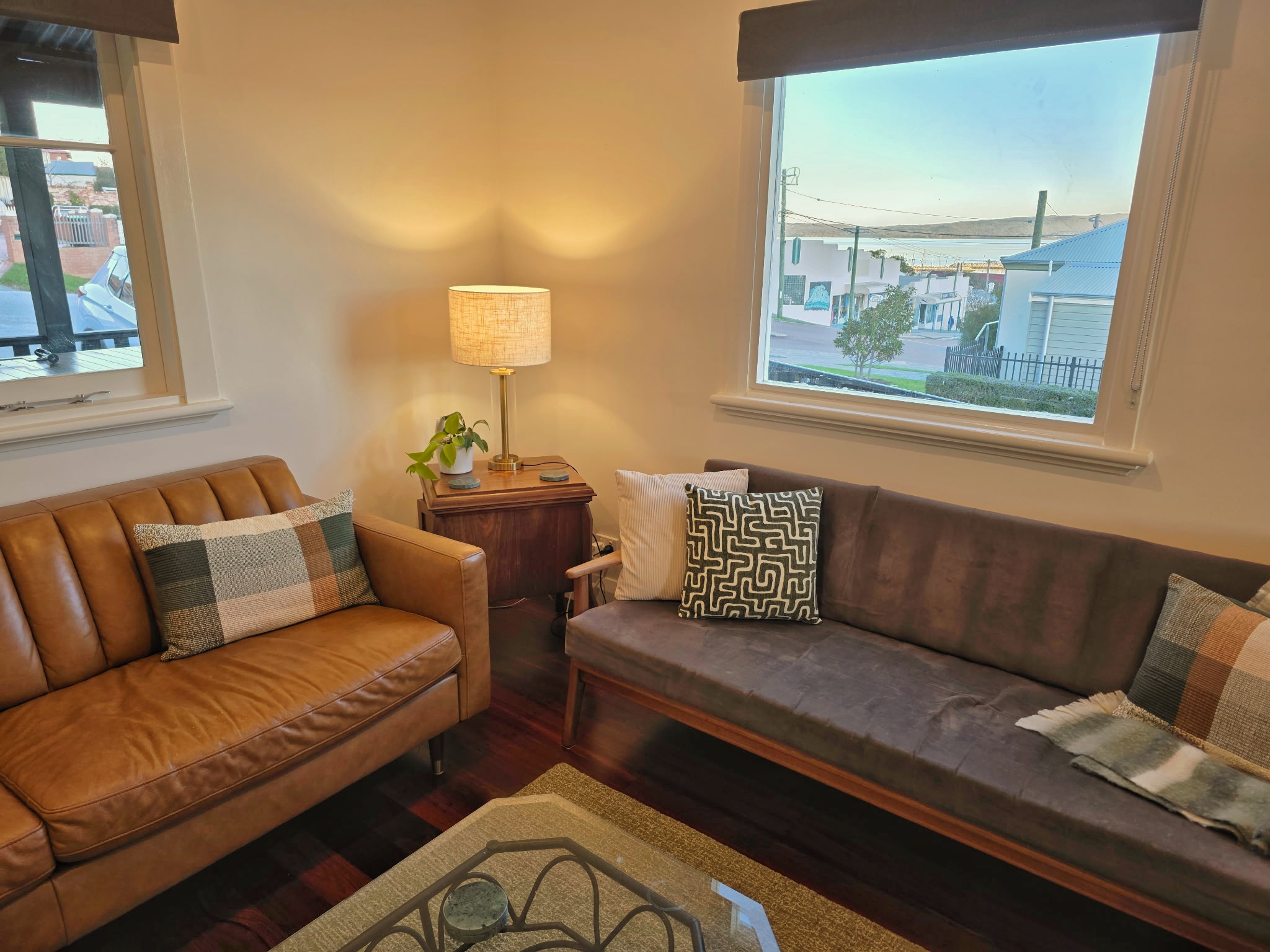 Lounge with leather sofa, window-side seating, warm lamp light and a harbour view